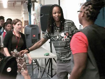 Backpack'd: Kelsie Norman, middle, gave away more than 100 backpacks to middle school students at TechBoston Academy on Monday. 	Photo by Bill Forry